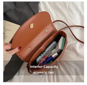 Brown leather saddle bag showing internal capacity for phone and makeup accessories