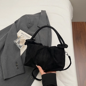 Sac à main plissé noir chic avec poignée ronde sur un fond esthétique minimaliste