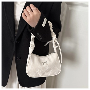 Gros plan sur le sac croissant blanc plissé avec nœud argenté et bandoulière froncée