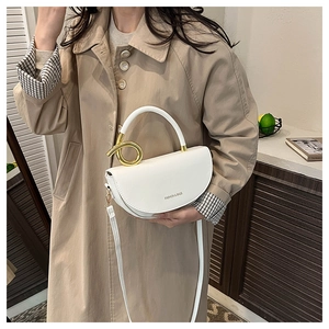 Detail of white saddle bag showing gold metal twist handle and faux leather texture
