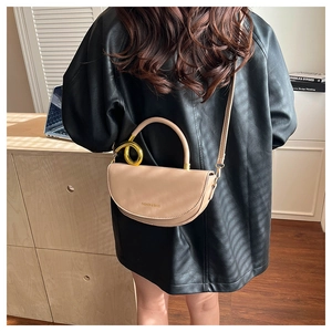 Close-up of beige saddle bag featuring gold metal rings and 'Fashion & Bags' lettering