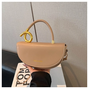 Detail of elegant beige leather saddle bag with distinctive golden metal ring handle