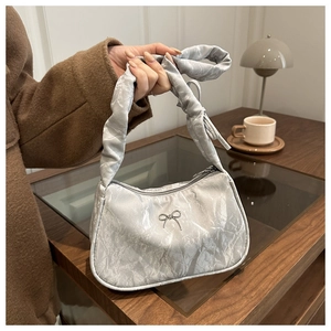 Détail du sac croissant en satin plissé argenté avec nœud métallique et anse en ruban noué