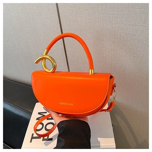 Detail of orange saddle bag with gold spiral handle and FASHION & BAGS text