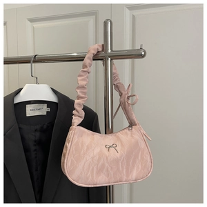 Détails de la texture d'un sac sous les bras rose plissé avec nœud métallique