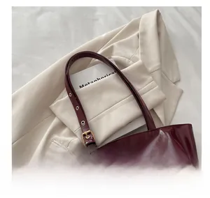 Top view of deep burgundy wax leather tote with golden buckle details and glossy finish
