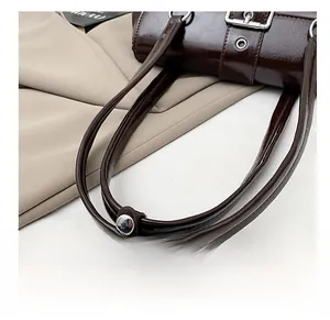 Detail of adjustable double straps with silver buckles on a vintage brown leather bag