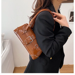 Macro view of vintage brown leather shoulder bag with metallic buckle and silver rivets