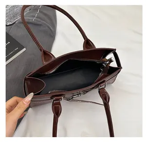 Detail view of the spacious black interior and silver zipper of this dark brown handbag