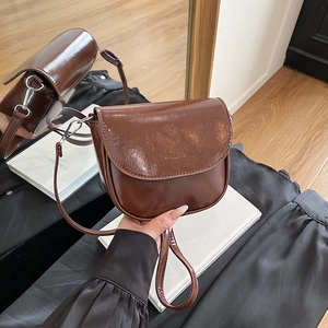 Brown patent leather saddle bag with semi-circular design and adjustable thin strap