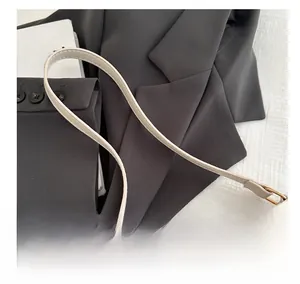 Nahaufnahme der beigen Jacquard-Handtasche mit M-Muster und goldenen Metallschnallen