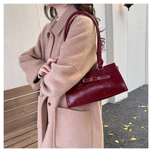 Detail of dark red leather baguette bag with silver eyelets in autumn setting