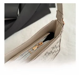 Detail des goldenen Reißverschlusses und der M-Jacquard-Muster auf der beigen Tasche