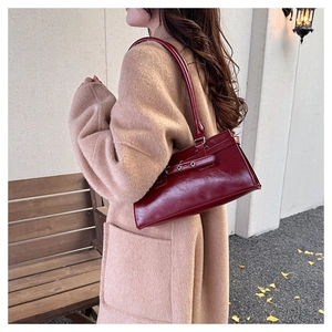 Detail of dark red vintage faux leather shoulder bag with metallic buckle on a model