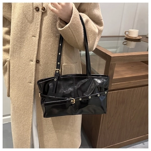 Detail of glossy black oil wax leather handbag with golden buckles and metal eyelets
