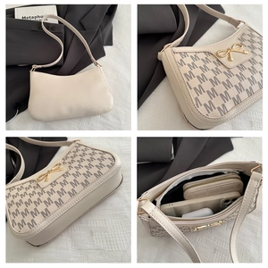 Detailansicht der beigen Monogramm-Tasche mit goldener Schleife und Innenraum-Details