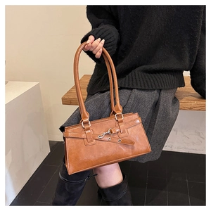 Detail of caramel brown leather handbag with silver hardware and vintage shoulder strap