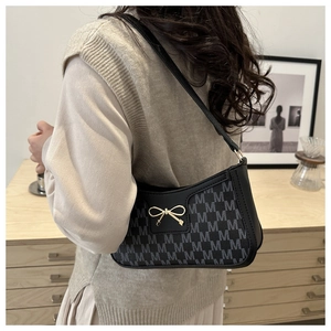 Detail der schwarzen Achseltasche mit M-Muster und goldener Schleifenschnalle