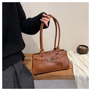 Detail of caramel brown faux leather shoulder bag with decorative straps and silver buckle