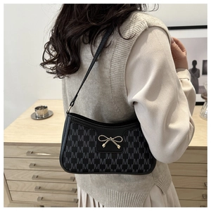 Nahaufnahme einer schwarzen Monogramm-Achseltasche mit eleganter goldener Schleife