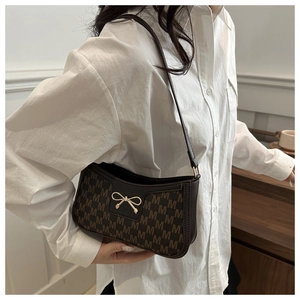 Detailansicht einer Vintage-Schultertasche in Dunkelbraun mit goldener Schleife und Muster
