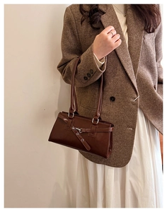 Detail of vintage dark brown faux leather shoulder bag with decorative belt buckle detail
