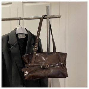 Close-up of brown polished oil wax leather shoulder bag with decorative metal eyelet belts