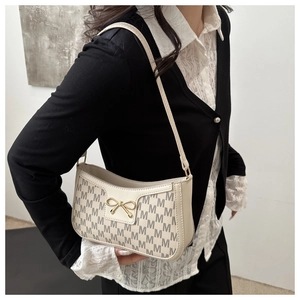 Detailansicht der cremefarbenen Monogramm-Tasche mit goldener Schleifenschnalle
