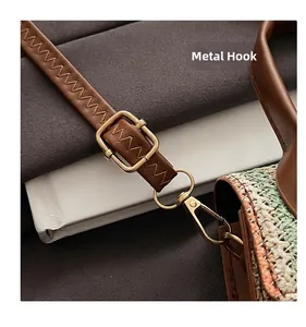 Close-up of golden hardware hook and adjustable leather strap on a woven crossbody bag