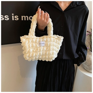 Détail du sac plissé blanc avec étiquette Love Fashion porté sur une robe noire