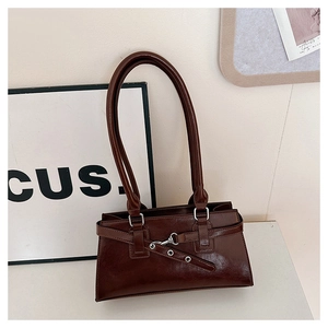 Detailed view of dark brown glossy leather shoulder bag with vintage silver buckle strap