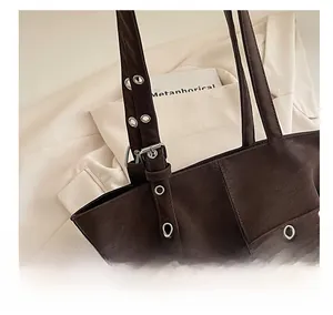 Detail of retro brown suede tote bag featuring adjustable leather strap and metal eyelets