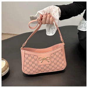 Detailaufnahme der rosa Kunstledertasche mit Buchstabendruck und goldener Schleife