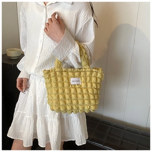 Détail du sac à main jaune à texture gaufrée avec étiquette blanche en tissu tendance