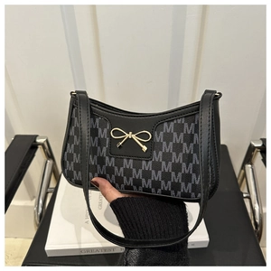 Detail der grauen Schultertasche mit M-Monogramm und schicker goldener Schleifenschnalle