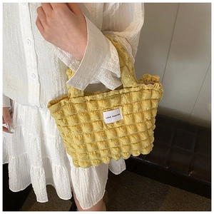 Gros plan du sac à main jaune texturé bulles avec étiquette LOVE FASHION et tissu doux