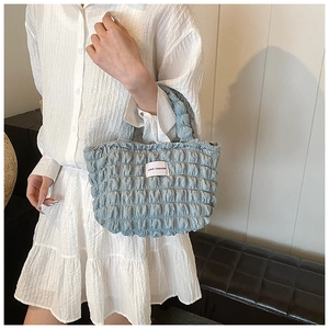Détail du sac bleu clair à texture nuage montrant le tissu plissé et l'étiquette mode