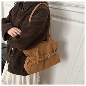 Detail of camel leather underarm bag with decorative belt straps and silver metal buckles