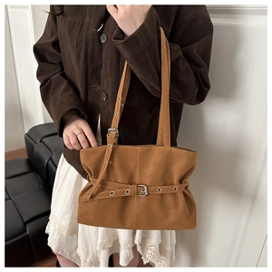 Detail of vintage pleated brown shoulder bag with metal buckle on model underarm