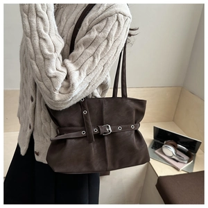 Detail of dark brown soft leather shoulder bag with metallic eyelet belt decoration