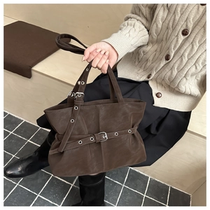 Detail view of brown biker-style shoulder bag with silver hardware and buckle straps