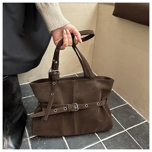Close-up of vintage dark brown tote bag with metal eyelets and adjustable strap detail