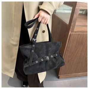 Detail of black suede handbag featuring silver belt buckles and vintage metal eyelets