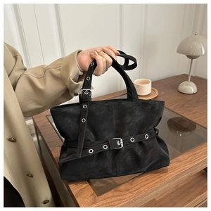Detail of black matte hobo bag with silver buckle strap and textured finish
