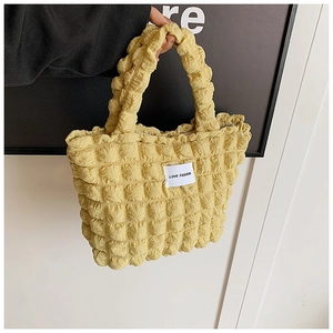 Détail du sac cabas jaune à texture popcorn avec étiquette Love Fashion à la main