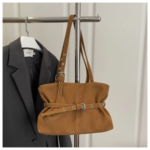 Detail of vintage brown faux suede tote bag with belt buckle and metal eyelets on a hanger