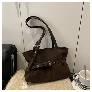Detail of dark brown suede shoulder bag with decorative buckle and textured strap