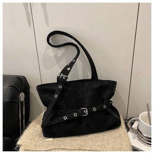 Detail of silver metal eyelets and belt buckle design on a black suede tote bag