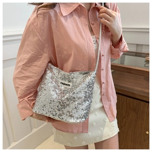 Détail du sac à bandoulière à paillettes argentées avec écusson mode sur chemise