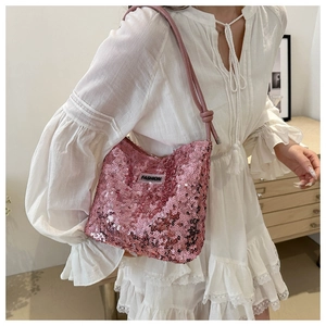 Détail du sac à bandoulière à paillettes roses avec étiquette FASHION et nœud